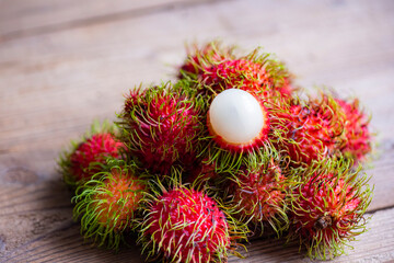 Fresh and ripe rambutan sweet tropical fruit peeled rambutan with leaves, Rambutan fruit on wooden...