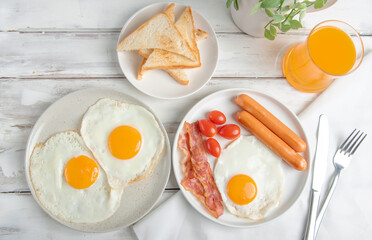 Morning breakfast with fried eggs, bacon,sausage,orange juice and toasts bread.