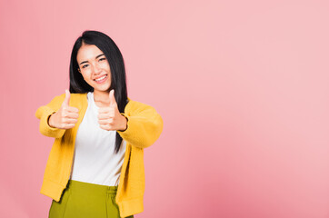 .Portrait Asian beautiful young woman smile she standing made finger thumbs up, Ok sign to agree studio shot isolated on pink background, Thai female successful like finger gesture with copy space