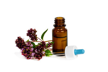 oregano flowers with opened brown bottle and dropper on white background