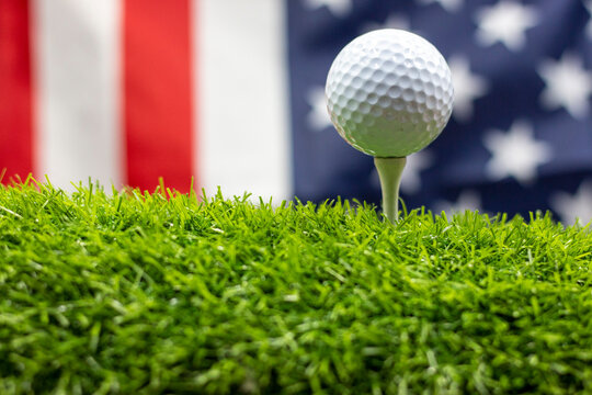 Golf ball with flag of America on green grass background