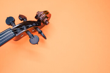 Pegbox of a violin on orange background with a copy space