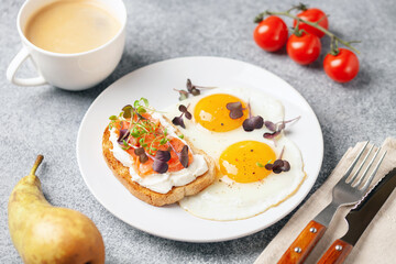 Eggs with microgreens and sandwich with cheese and salmon. Healthy breakfast