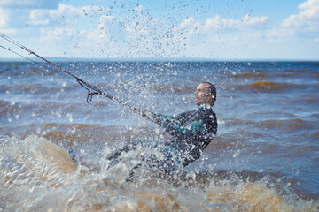 Kiteboarder surfing waves with kiteboard on a sunny summer day.