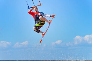 Kiteboarder surfing waves with kiteboard on a sunny summer day. A man performs a trick-jump on a surfboard.