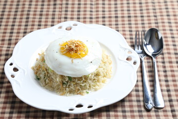 wok garlic olive fried rice with small silver fish seafood, fried egg and vegetables on white plate asian halal menu