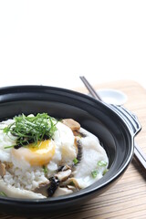 chef cook Hong Kong congee porridge with mixed seafood unagi, fish, prawn, squid, mushroom, egg and vegetables in black hot clay pot , chopstick spoon asian healthy halal menu