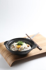 chef cook Hong Kong congee porridge with mixed seafood unagi, fish, prawn, squid, mushroom, egg and vegetables in black hot clay pot , chopstick spoon asian healthy halal menu