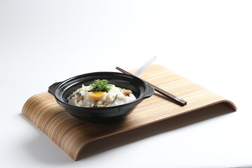 chef cook Hong Kong congee porridge with mixed seafood unagi, fish, prawn, squid, mushroom, egg and vegetables in black hot clay pot , chopstick spoon asian healthy halal menu