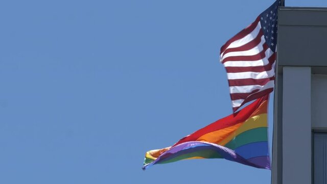 Unites States and gay pride flag blowing together in the wind
