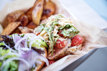 Asian tuna sandwich with tomatoes and potato wedges.