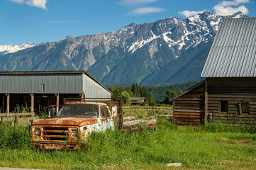 A derelict truck lies beside an organic farm with Mt. Currie in the background.  Pemberton BC,...