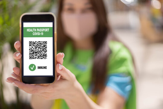 Portrait travel woman in face mask with digital app health passport covid19 qr code on smartphone