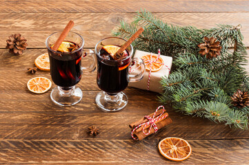 Mulled red wine with spices. Christmas decoration with dried orange slices. cinnamon sticks and christmas presents on wooden background