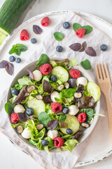 Fresh summer salad with arugula, mozzarella cheese, herbs and berries