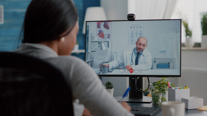 Sick black woman discussing with therapist doctor about sickness diagnosis explaining clinic test result on videocall conference meeting. Student working remote from home during medical appointment