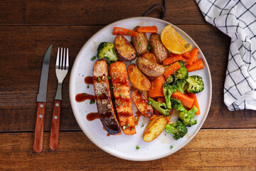 Homemade Grilled Salmon Steak with Broccoli, Potatoes, Carrots in a plate on a wooden table