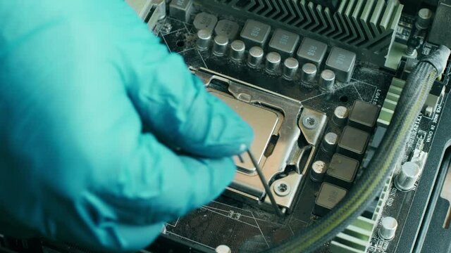 Electronics Repair Technician with a blue glove carefully remove a computer processor from an old dusty socket on a desktop computer motherboard. Inside view of a personal computer system. Close up 