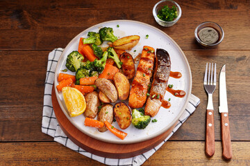 Homemade Grilled Salmon Steak with Broccoli, Potatoes, Carrots in a plate on a wooden table