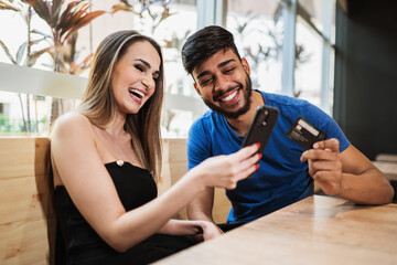 Young couple online banking using smartphone shopping online with credit card at balcony of your...