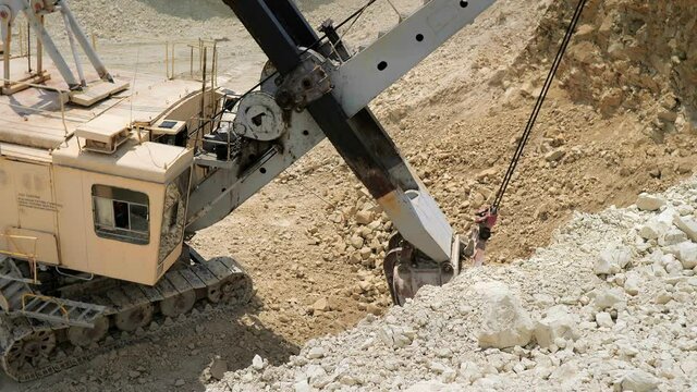 Excavator on earthworks. Quarrying and mining of rocks. Excavation work on a construction site. The territory of the cement plant. Industrial enterprise for cement processing