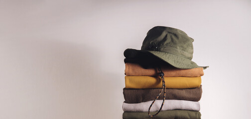 Clothes Concept. Stack of Clothing by the White Wall. Organic Cotton, Earth Tone - obrazy, fototapety, plakaty