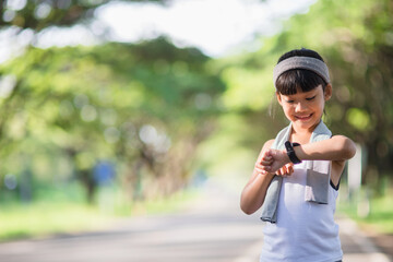 happy child girl running in the park in summer in nature. warm sunlight flare. asian little is running in a park. outdoor sports and fitness, exercise and competition learning for kid development.