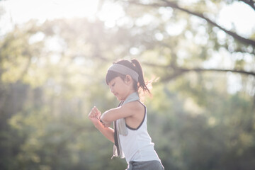 happy child girl running in the park in summer in nature. warm sunlight flare. asian little is running in a park. outdoor sports and fitness, exercise and competition learning for kid development.