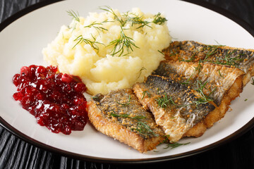 Fried herring fillets with mashed potatoes and lingonberry sauce close-up in a plate on the table. horizontal
