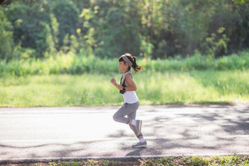 happy child girl running in the park in summer in nature. warm sunlight flare. asian little is running in a park. outdoor sports and fitness, exercise and competition learning for kid development.