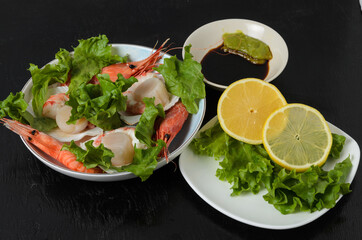 Natural raw scallop with boiled shrimp in the sink in a ceramic bowl with lettuce leaves and sauce...