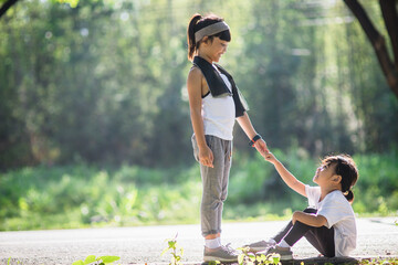 Naklejka premium Cute asian girl give hand to help sister accident during running