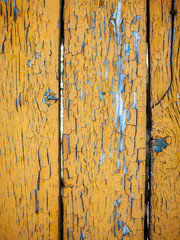 Wood texture with yellow flaked paint. Peeling paint on weathered wood