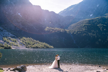 The bride and groom near the lake in the mountains. A couple together against the backdrop of a mountain landscape.