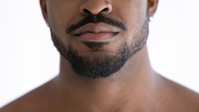 Close up of groomed beard of mixed race African guy with nose piercing, lower face with trimmed black stylish stubble. Male beauty care, grooming, barber work concept