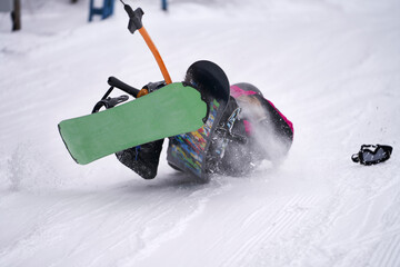 Two snowboarders lost their balance on a rope lift. They fell, but they do not let go of the rope...