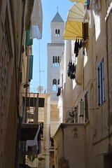 Bari, Italy.Narrow italian street with drying linen and Cathedral on the background.