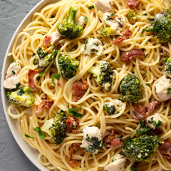 Homemade Chicken Bacon Broccoli Alfredo on a plate on a gray surface, top view. Overhead, from above, flat lay. Copy space.