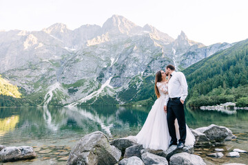 Romantic wedding couple in love standing on the rocky shore. Pic