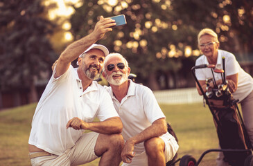 Senior golfers using phone and taking self portrait.
