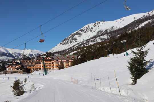 Snowy village on the top of the mountains with a chairlift crossing above the sky track in bariloche patagonia, la cathedral best skiing spot in south america