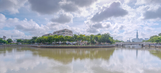 Fototapeta na wymiar Time: June 26, 2021. Location: Ho Chi Minh City. Panorama landscape photo: apartment building along Nhieu Loc - Thi Nghe canal (Vietnam)