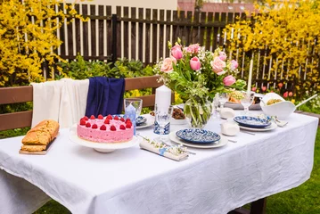 Fotobehang Selective focus photo. Celebration. Berry cake and decorated dinner table in garden. © Gints