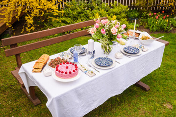 Selective focus photo. Celebration. Berry cake and decorated dinner table in garden.