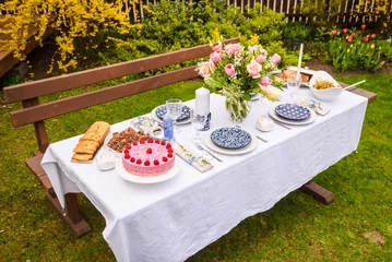 Poster Selective focus photo. Celebration. Berry cake and decorated dinner table in garden. © Gints