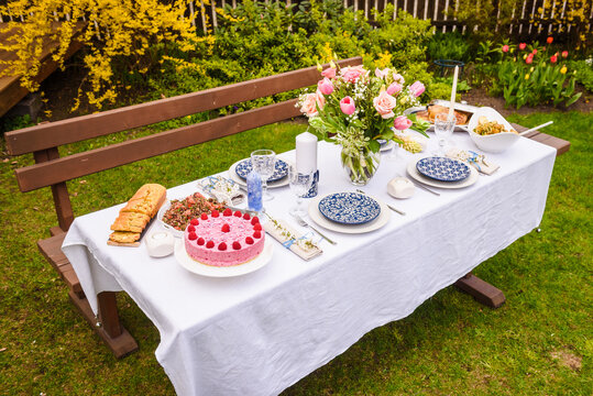 Selective focus photo. Celebration. Berry cake and decorated dinner table in garden.