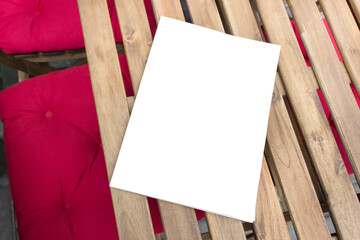 Mockup template of paper book with blank cover laying on wooden table on terrace of outside cafe.