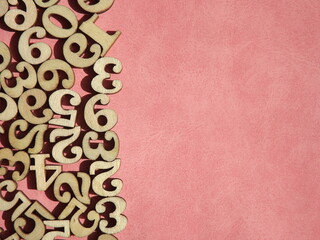 wooden numbers are randomly arranged on pink suede. High quality photo