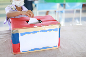 kid dropping vote or comment into box for giving in school society in living together