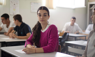  Teenagers students sitting in the classroom and writing.